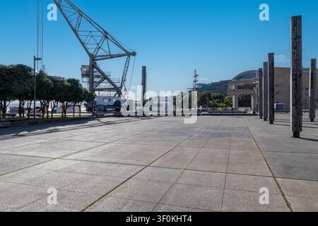 Autohintergrund, Automobil-Rückplatte, großer gepflasterter Parkplatz mit Hafen im Hintergrund Stockfoto