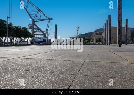 Autohintergrund, Automobil-Rückplatte, großer gepflasterter Parkplatz mit Hafen im Hintergrund Stockfoto