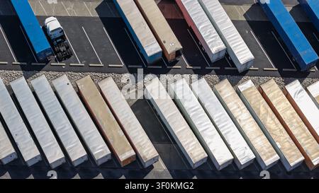 LKWs und Sattelanhänger, die an einem Logistikdepot geparkt sind, zeigen Transport und Versand Stockfoto