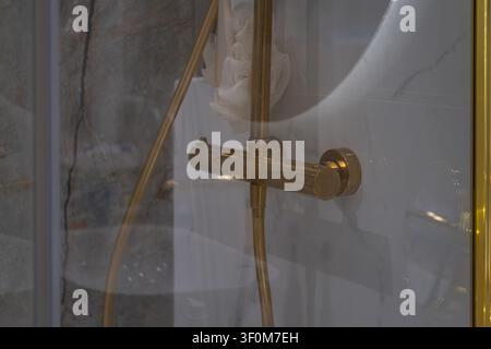 Nahaufnahme einer modernen Duschkabine mit zeitgenössischen Duscharmaturen hinter einer Glasabtrennung. Das Bild repräsentiert minimalistisches Badezimmerdesign Stockfoto