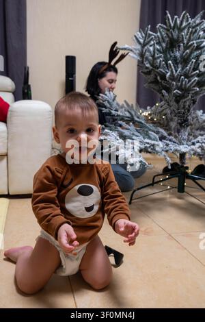 Kleinkind im Wohnzimmer beim Schmücken eines beflockten Weihnachtsbaums Stockfoto