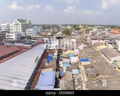 Luftaufnahme des Maeklong-Bahnmarkts mit einem Zug, der durch die engen Marktstände fährt, umgeben von dichten städtischen Dächern in Mae Klong, Samut S Stockfoto