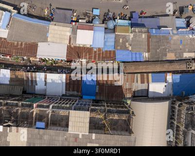 Luftaufnahme des Maeklong-Eisenbahnmarktes mit bunten Markisen und Metalldächern entlang der Bahngleise in Mae Klong, Samut Songkhram, Thailand. Stockfoto