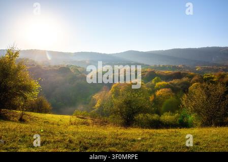 Eine weitläufige Herbsttal-Landschaft erstreckt sich über geschichtete bewaldete Hügel in der Vorlandregion des Kaukasus. Stockfoto
