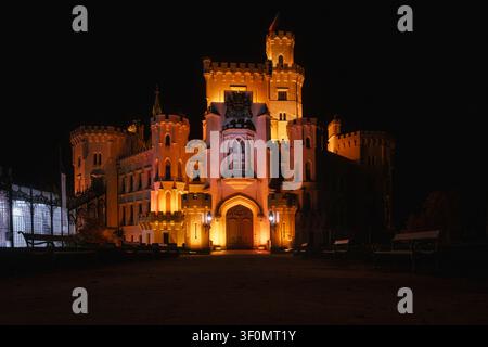 Beleuchtete Burg Hluboka nad Vltavou bei Nacht in Südböhmen, Tschechische Republik. Neogotische Architektur leuchtet vor dem dunklen Himmel. Stockfoto