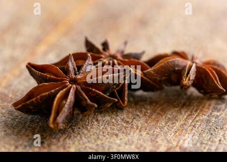 Drei Sternanis-Kapseln auf einem rustikalen Holzgrund. Aromatisches Gewürz, das beim Kochen, Backen und bei der natürlichen Lebensmittelstyling verwendet wird. Stockfoto