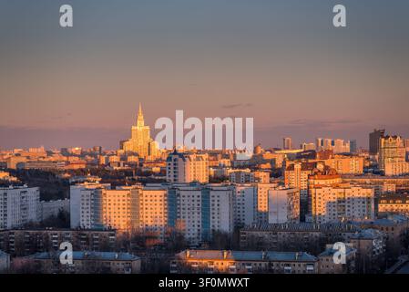 Erhöhte Panoramansicht der weitläufigen Stadtlandschaft Moskaus bei Sonnenuntergang, dominiert von einem der berühmten Sieben-Schwester-Wolkenkratzer Stalins, erkennbar an seinem Stockfoto