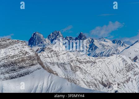 Eine Panoramansicht schroffer, schneebedeckter Gipfel, die über geschichteten Alpenkämmen im Großen Kaukasus aufragen Stockfoto