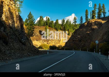 Eine zweispurige Asphaltautobahn windet sich durch einen dramatischen Felsschnitt am Chuysky Trakt (Chuya-Autobahn). Stockfoto