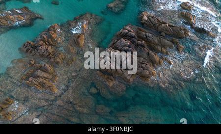 Vertikale Luftaufnahme von felsigen Riffen, flachem Mittelmeerwasser und Küstenmeertекстuren nahe Propriano im Golf von Valinco in Propriano, Korsika Stockfoto