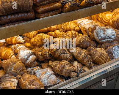 Verschiedene buttrige Backwaren, die in Ladenregalen angeordnet sind, mit Schwerpunkt auf biologischen Zutaten, Gourmet-Backtraditionen und dem einladenden Charme eines Lo Stockfoto