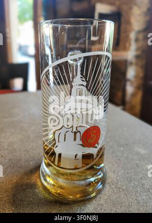 Ein fast leeres Bierglas der Marke Soproni auf einem Betontisch in einer Restaurantatmosphäre, mit geringer Schärfentiefe Stockfoto