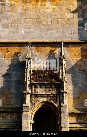 Gotische Steintür mit verzierten Pinakeln und einem kleinen Dach aus Ziegeln, auf dem Pflanzen wachsen, All Saints Church, Stamford, Lincolnshire, UK. Stockfoto