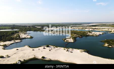 Luftbild eines Sandsteinbruchs mit mehreren blauen Seen und weißen Sandufer, das industrielle Wasserabbau zeigt Stockfoto