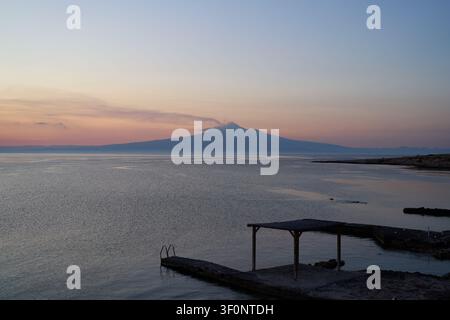 Rauchender Ätna, der bei Sonnenuntergang von Brucoli aus über das Meer gesehen wird Stockfoto