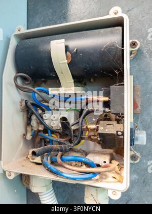Nahaufnahme eines alten elektrischen Steuerkastens mit freiliegender Verkabelung, Staub, Korrosion und Spinnweben. Konzept von Wartung, elektrischer Sicherheit, Inspektion, Alter Stockfoto
