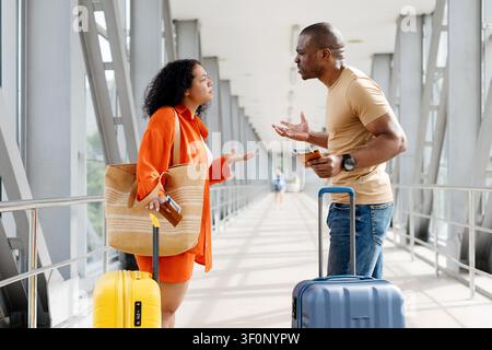 Junges schwarzes Paar hat einen angespannten Streit am Flughafenterminal Stockfoto