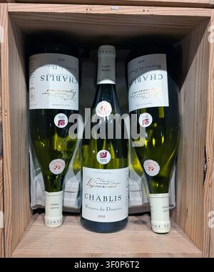 JUVISY, FRANKREICH - 27. September 2025. Regale in einem Supermarkt präsentieren eine Vielzahl von Chablis-Weißweinflaschen, die ordentlich in einer Holzkiste angeordnet sind. Cust Stockfoto