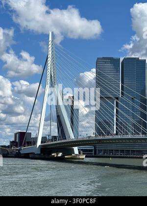 Erasmus-Brücke und moderne Wolkenkratzer über dem Fluss in Rotterdam. Eine große Hohlkastenbrücke spannt sich unter einem wunderschönen blauen Himmel über das Wasser w Stockfoto