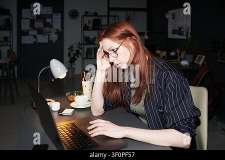 Erwachsene Frau arbeitet spät am Laptop und erlebt Burnout Stockfoto