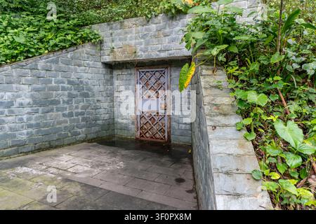 Eisentor, umgeben von einer Steinmauer im Gartenweg. Stockfoto