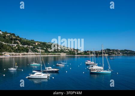 Sonnige Panoramasicht von Yachten und Segelbooten, die in der blauen Bucht von Villefranche-sur-Mer, Französische Riviera, vor Anker liegen. Perfektes Luxusreise-Asset Stockfoto