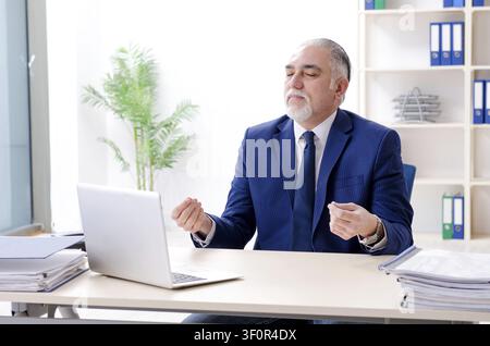 Alter Geschäftsmann Yoga Übungen im Büro Stockfoto