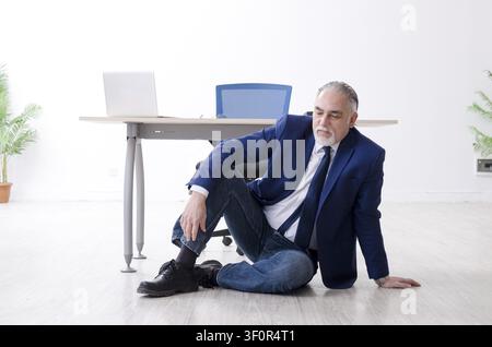 Alter Geschäftsmann Yoga Übungen im Büro Stockfoto