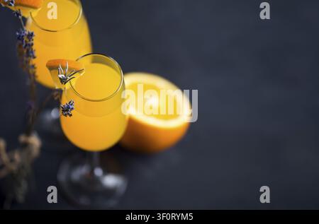 Erfrischender Mimosa-Spritzwein-Cocktail in Gläsern mit Champagner und Lavendelfloren Kopierraum Stockfoto