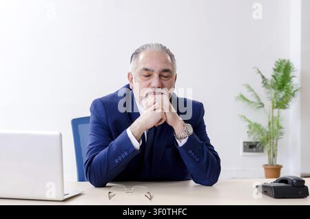 Alter Geschäftsmann Yoga Übungen im Büro Stockfoto