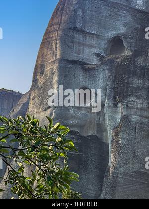 Kalambaka, Griechenland - 24. Juli 2024: Meteora-Gruppe von Klöstern. Einer der steilen Felshänge und Klippen. 2 Höhlenöffnungen sichtbar Stockfoto