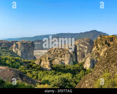 Kalambaka, Griechenland – 24. Juli 2024: Meteora-Gruppe von Klöstern. Kloster der Heiligen Dreifaltigkeit auf seinem Felsplateau, mit weit unten der Stadt Kalambaka Stockfoto