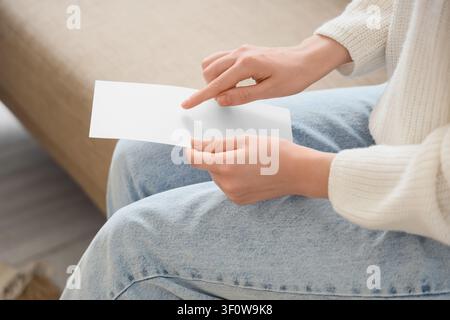 Frauenhände halten ein leeres weißes Blatt Papier oder einen Umschlag und zeigen auf den leeren Raum für Text oder Design, Kommunikation und Nachricht Stockfoto