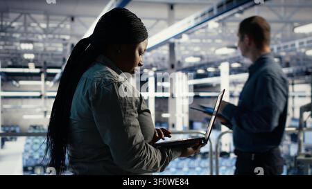 Der Administrator des Rechenzentrums verwendet einen Laptop, um Deep Learning-Prozesse zu überwachen und mit KI-Technologie und Hochleistungssystemen zu arbeiten. Stockfoto