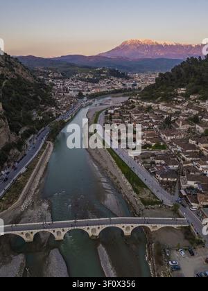 Luftaufnahme der historischen Stadt Berat mit dem Osum-Fluss und der Gorica-Brücke, umgeben von traditionellen Häusern und schneebedeckten Bergen in Berat Stockfoto