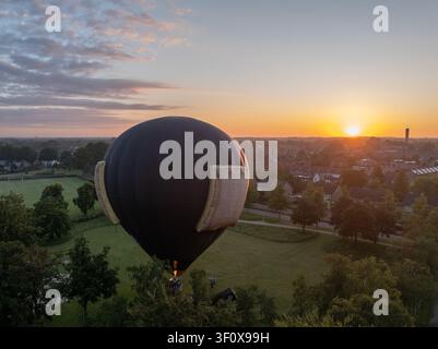 Luftbild eines schwarzen Heißluftballons, der über einer Wohnstadt in den Niederlanden schwebt. Stockfoto