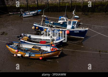 Fischerboote, die bei Ebbe im Amble Harbour auf dem Schlamm gestrandet sind Stockfoto