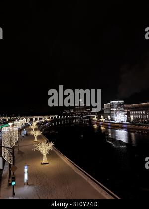 Moskau, Russland - 22. Januar 2022: Festliche beleuchtete Uferpromenade und Flussufer-Stadtlandschaft während der Winternacht in Moskau Stockfoto