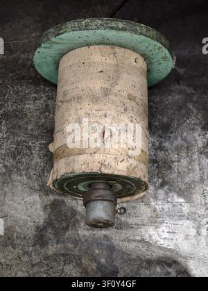 Holzspule stationär, auf Betonoberfläche, mit Holzspule, Metallbasis, mit Holz-, Metalltextur, aus einer Vogelperspektive, mit Grün, Braun Stockfoto