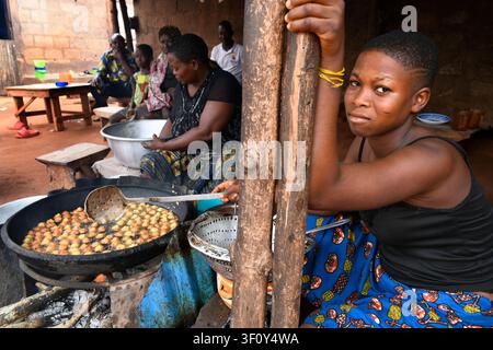 Frauen bereiten traditionelle frittierten Speisen vor einem Familienhaus in Ganvié, Benin. Frische Akara-Fritters werden über einem Holzofen gekocht, während Verwandte Stockfoto