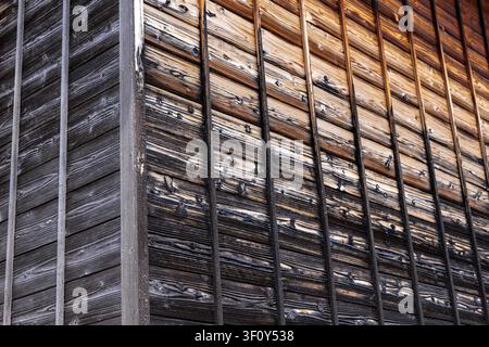 Verwitterte Holzplanken, die eine Außenwand altern lassen Stockfoto