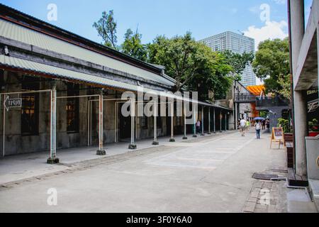TAIPEI, TAIWAN – 15. FEBRUAR 2022: Touristen gehen auf einem Weg neben historischen Fabriklagergebäuden und einem rostigen Metallpavillonsaal a Stockfoto