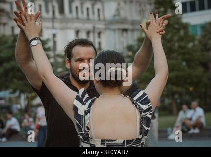 Mann lächelt, während er im Freien mit einer Frau tanzt Stockfoto