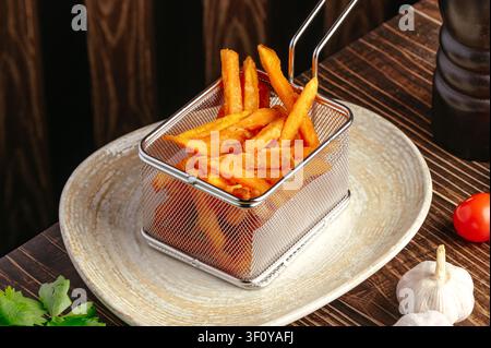 Süßkartoffel-Pommes in einem Mini-Fritteusen-Korb serviert Stockfoto