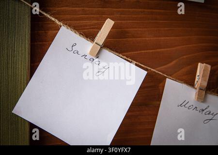 Leere Wochenplan-Notizen, die an einer Wäscheleine mit Holzklammern hängen Stockfoto