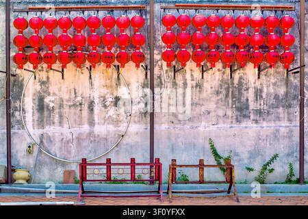Reihen roter chinesischer Laternen, die an einer verwitterten Kolonialmauer im chinesischen Erbeviertel von George Town hängen. Penang, Malaysia. Stockfoto