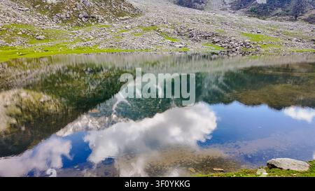 Eine Hochwinkelansicht des Kareri-Sees in Himachal Pradesh, die klares Wasser zeigt, das den Himmel und die felsigen Berge widerspiegelt. Stockfoto