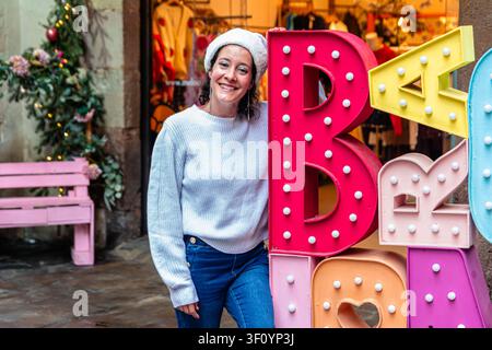 Junge Frau lächelt in Weihnachtsmannmütze während der Weihnachtseinkaufszeit Stockfoto