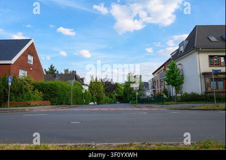 Deutsche Wohnstraße mit Häusern, Asphaltstraße, grünen Hecken und Geschwindigkeitsschild. Stockfoto