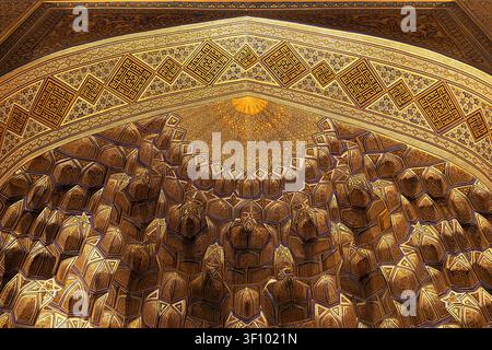 Vergoldete Muqarnas-Decke im Gur-e-Amir-Mausoleum in Samarkand, Usbekistan. Verschlungene islamische geometrische Muster und Kalligrafie schmücken die Kuppel inte Stockfoto